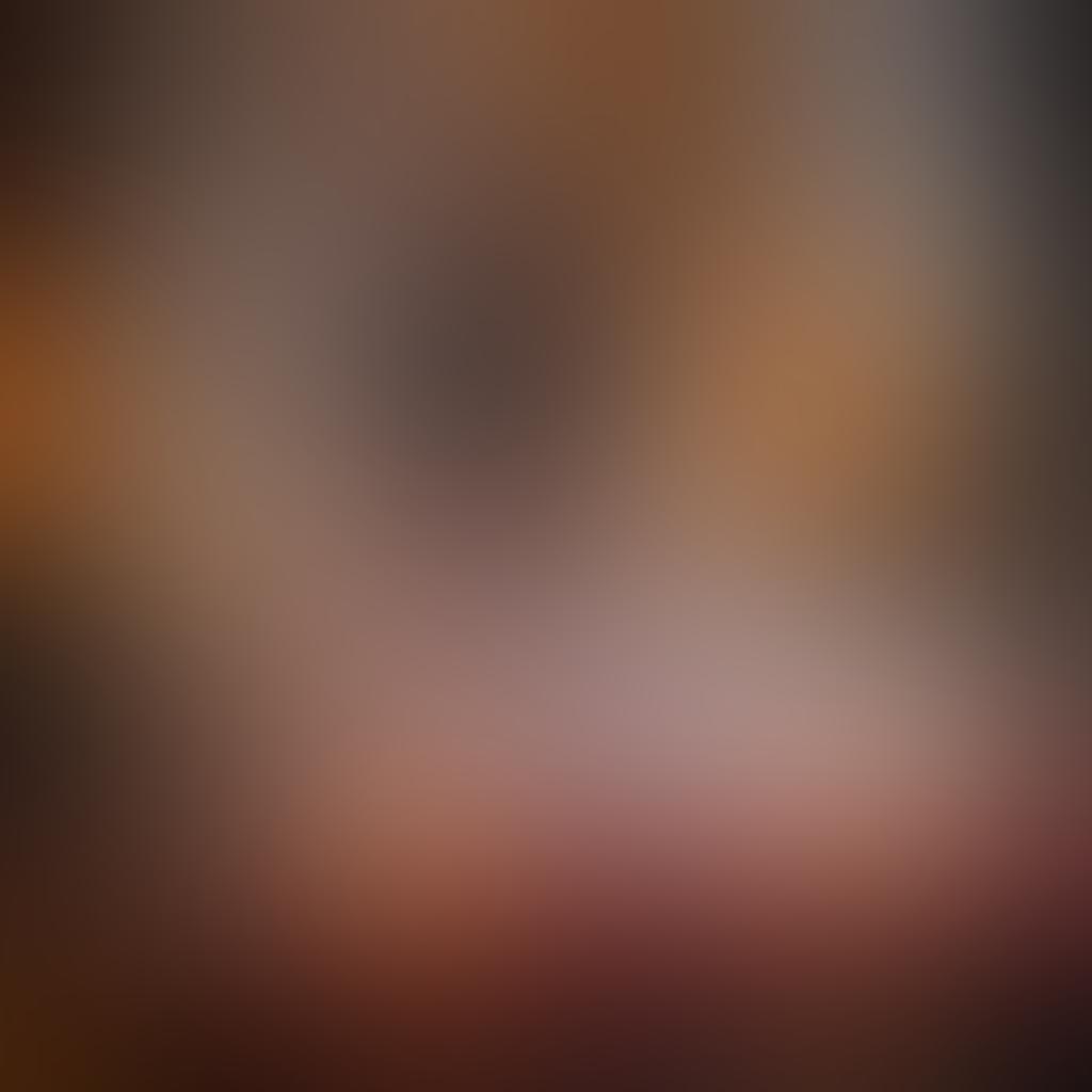 A romantic setting with a luxurious bed draped in silk sheets, soft candlelight flickering, and rose petals scattered. Include a couple intimately sharing a playful, flirtatious moment, with sensual expressions and playful body language, embodying passion and connection. The background should be filled with rich, warm colors to evoke desire, with subtle elements symbolizing fantasy, like soft feathers or silk masks. super-realistic. warm colors. moody lighting.